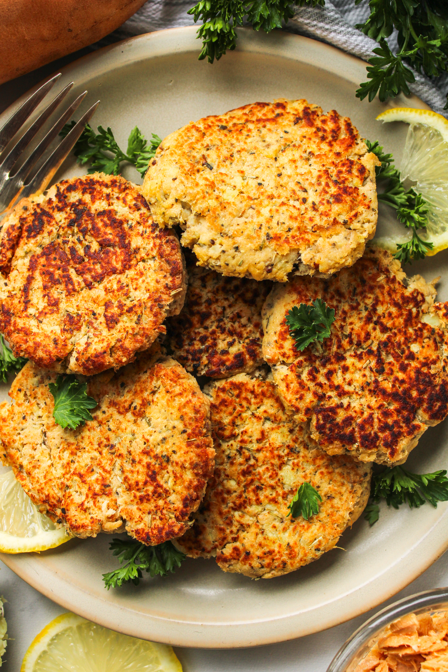 salmon sweet potato cakes on a grey ceramic plate topped with fresh parsley