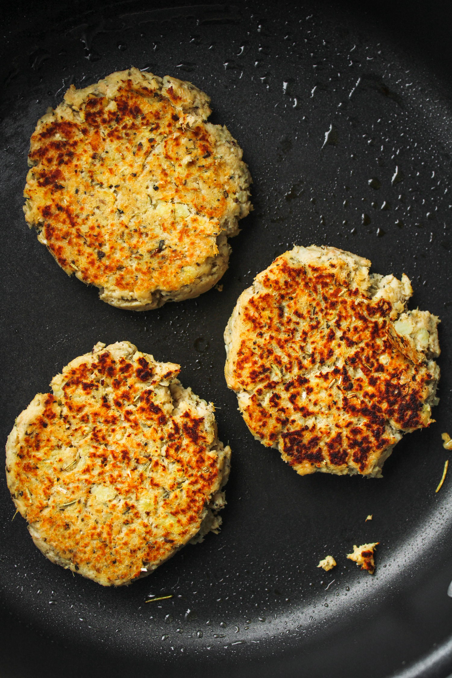 sweet potato salmon patties cooking on a black frying pan