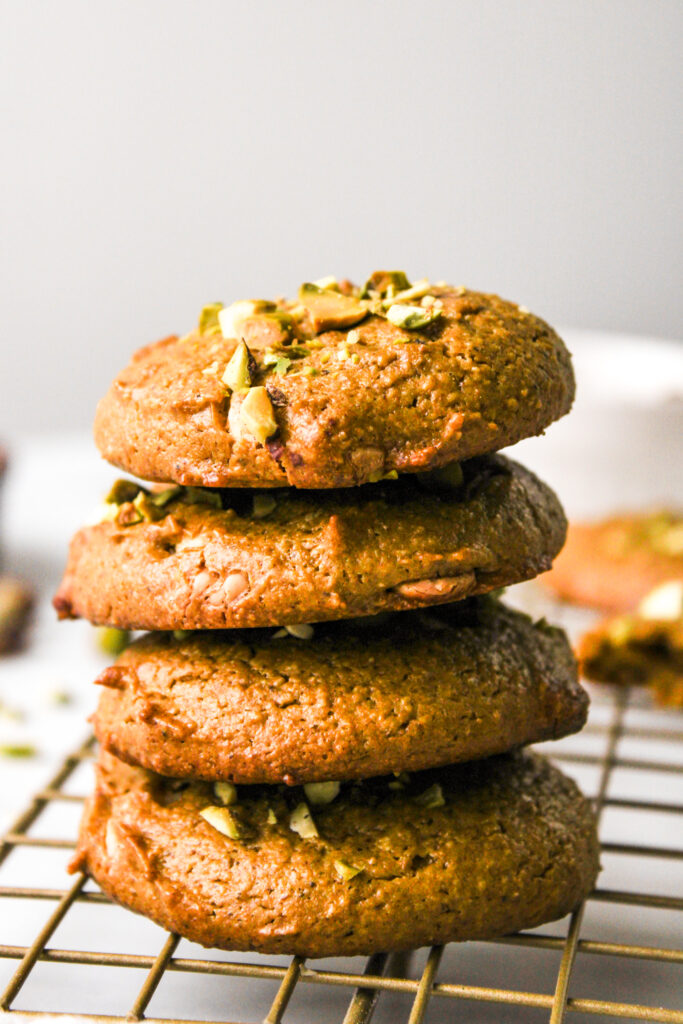 almond pistachio cookies stacked on top of each other on a cooling rack