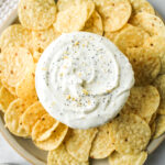 overhead shot of everything but the bagel dip in a white bowl surrounded by corn chips