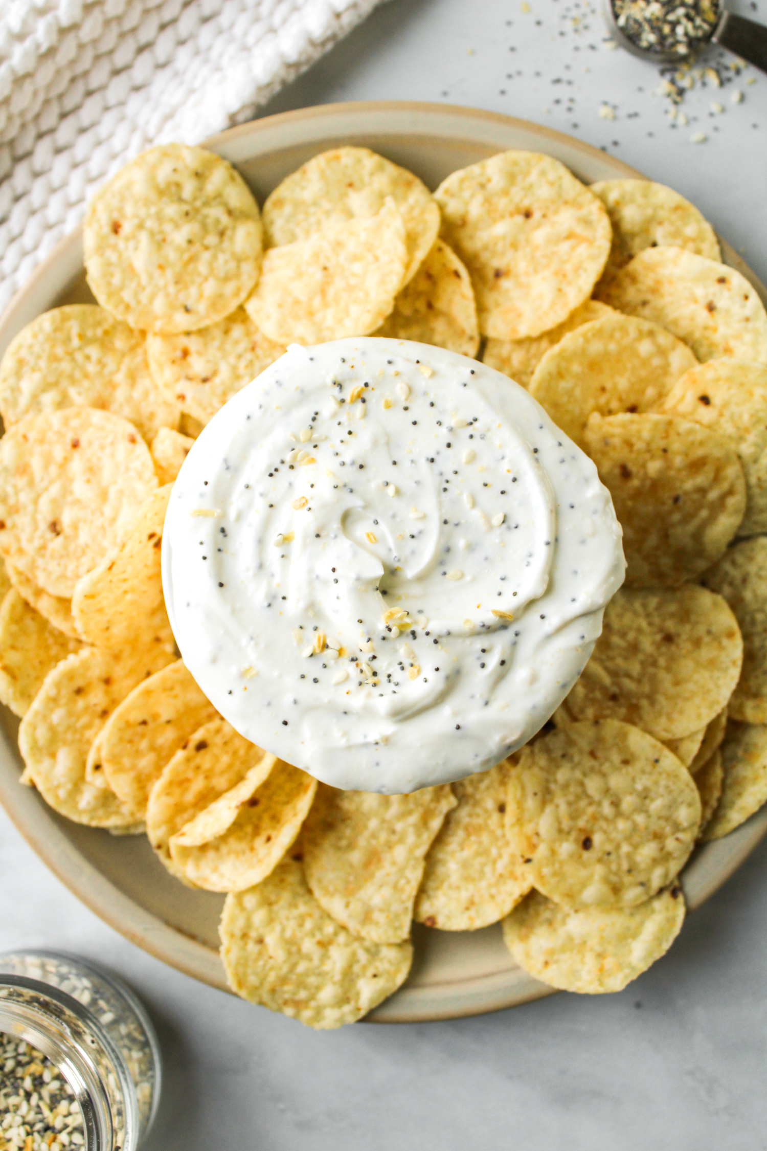 overhead shot of everything but the bagel dip in a white bowl surrounded by corn chips
