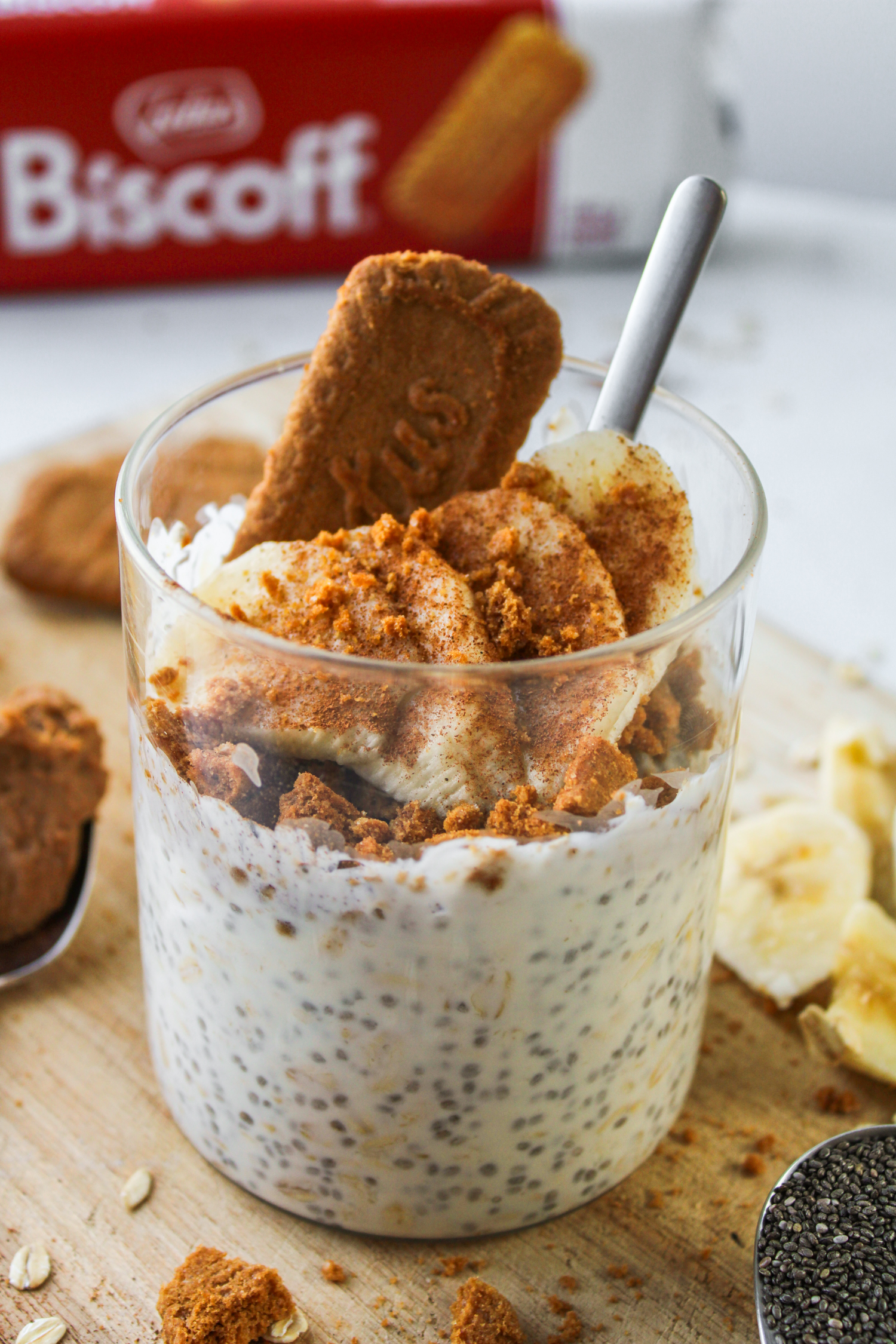 overnight oats topped with banana, cinnamon and a biscoff cookie sticking out of it, all in a glass container