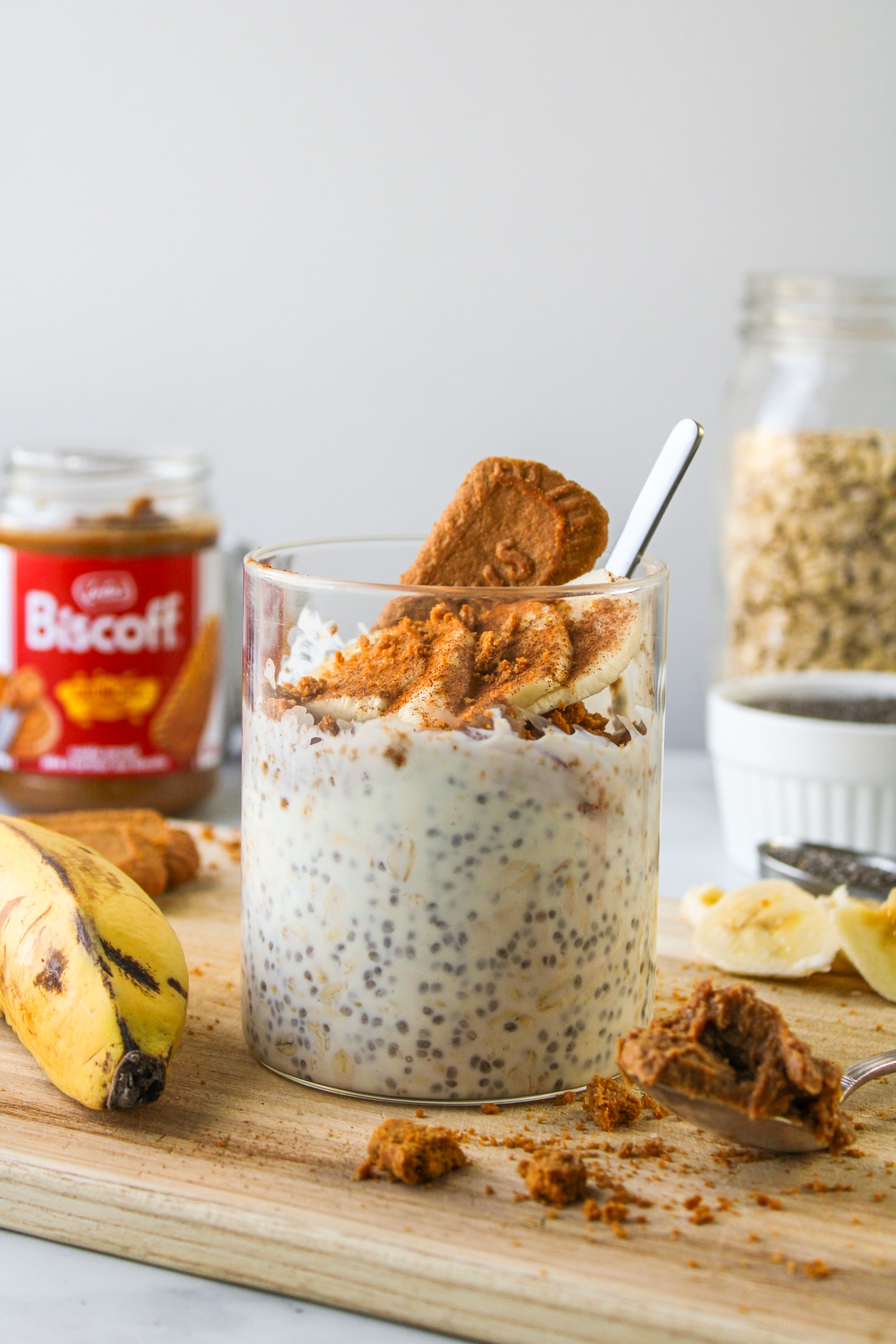 side profile of biscoff overnight oats in a glass container with ingredients surrounding it