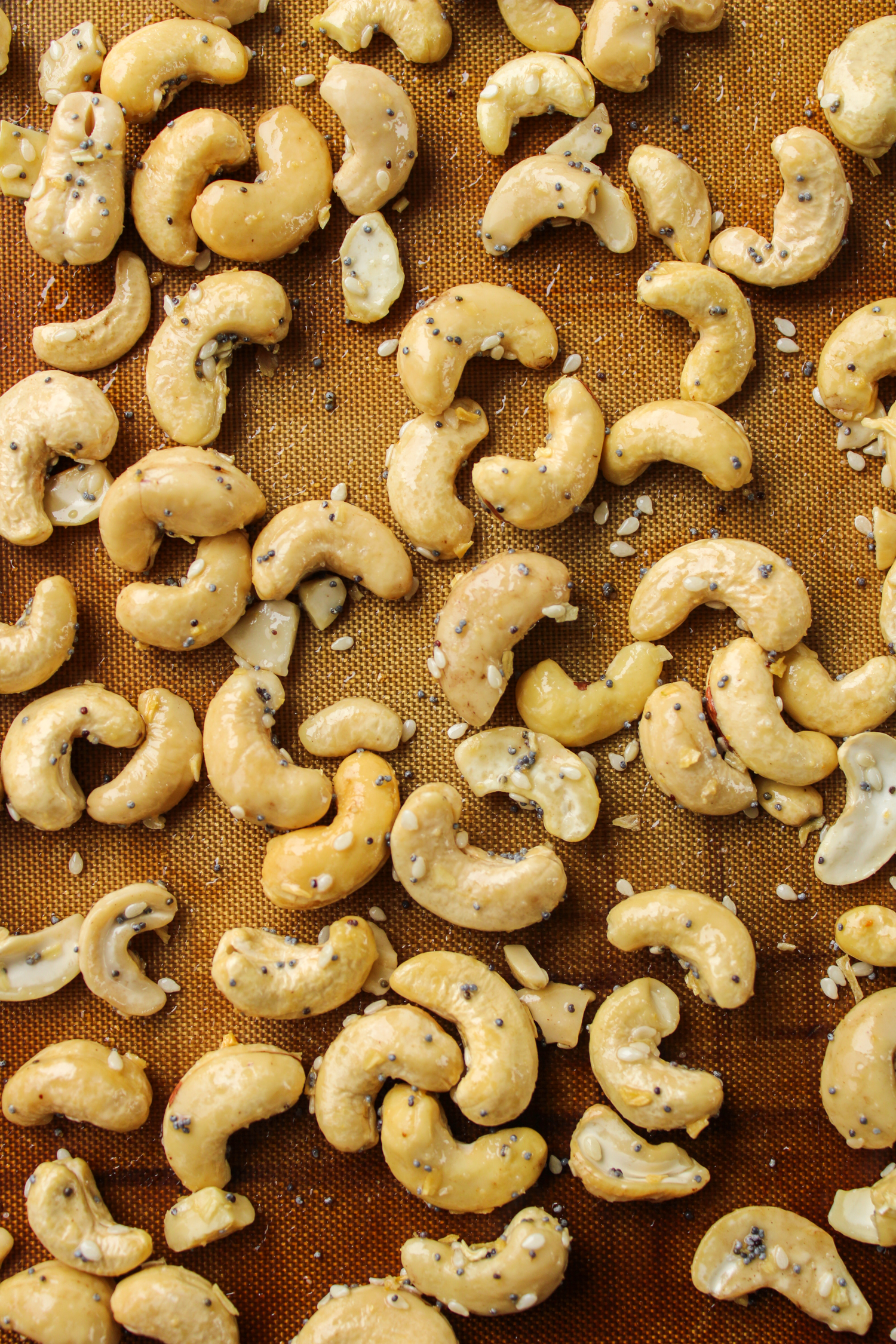 raw everything bagel cashews on a silicone baking mat on top of a baking sheet