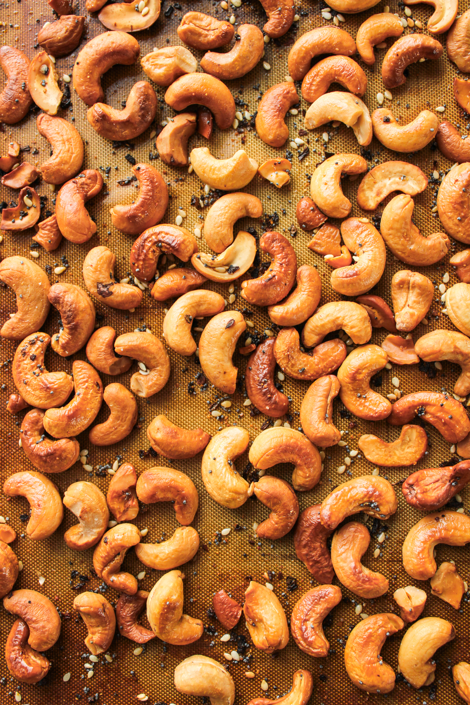 roasted everything bagel cashews on a silicone baking mat on top of a baking sheet