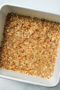 nut bar base crumb mixture pressed into a stainless steel square pan