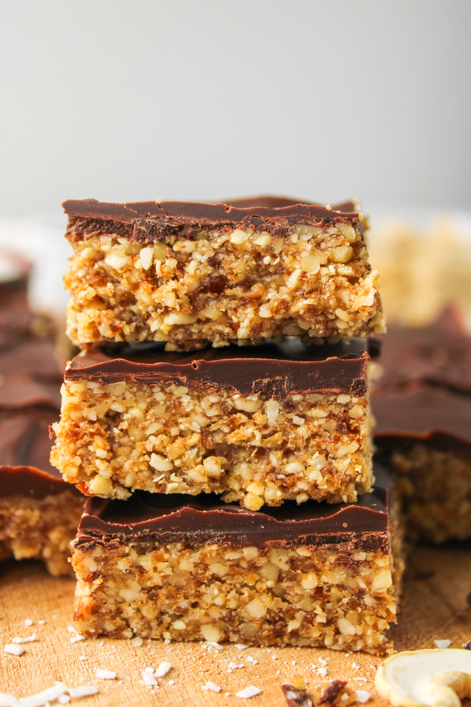 3 squares of cashew bar with chocolate coating stacked on top of each other, profile shot