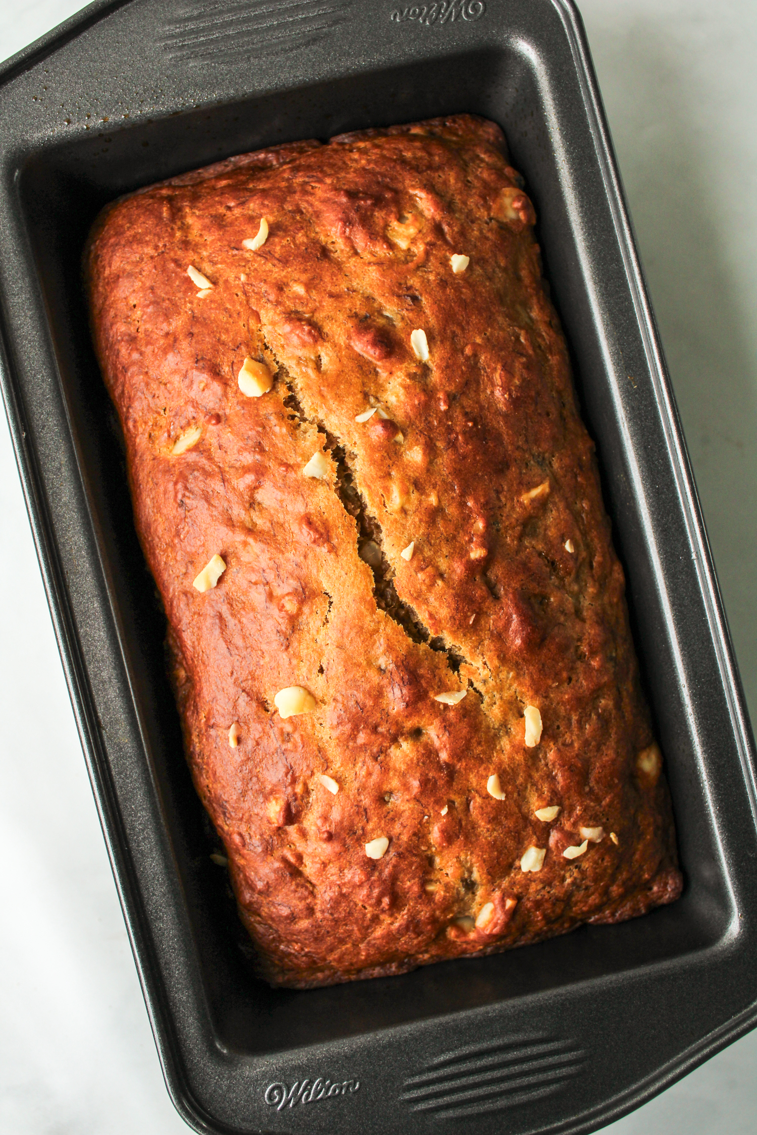 baked macadamia banana loaf in a black loaf pan