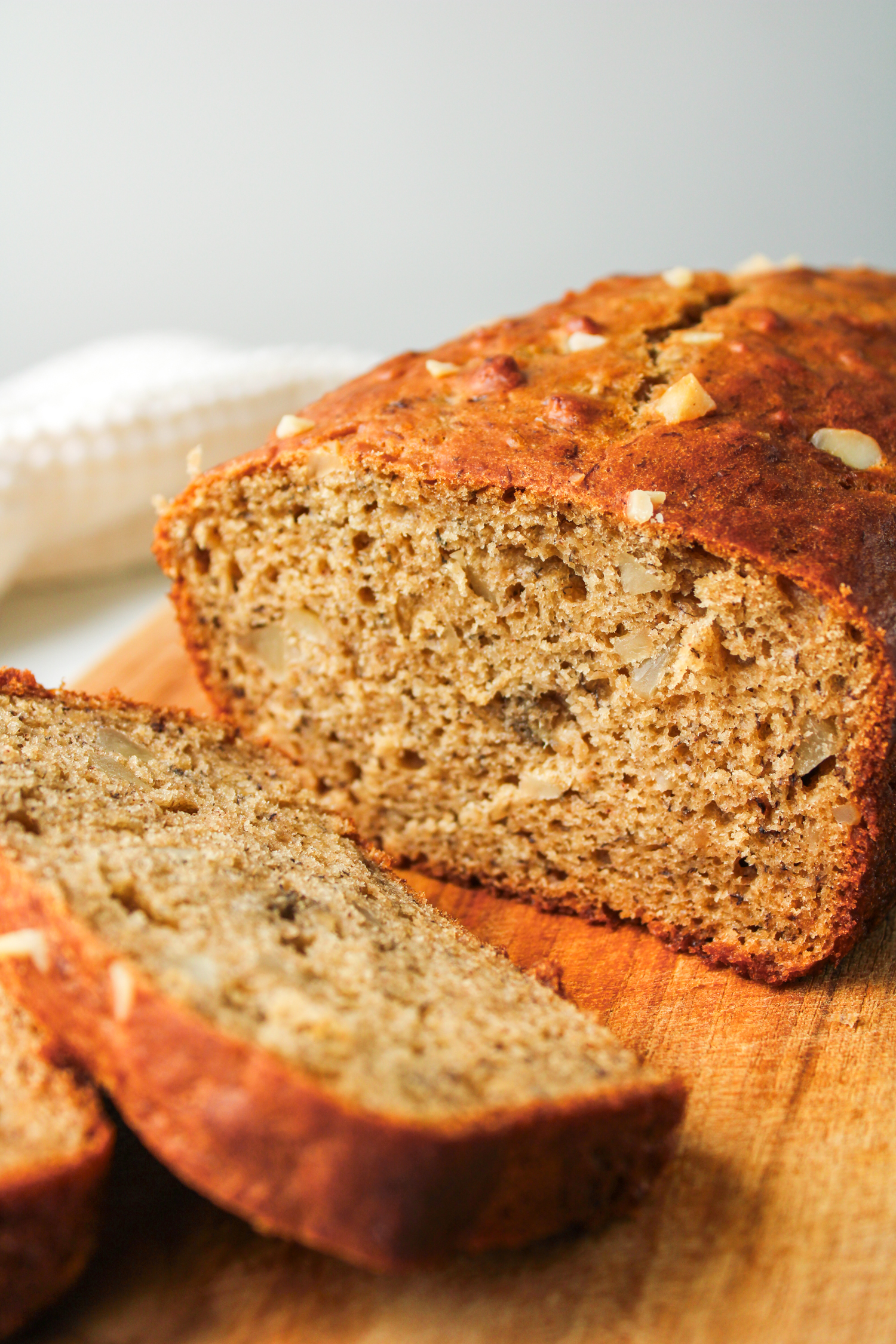 macadamia banana bread sliced on top of a wooden cutting board