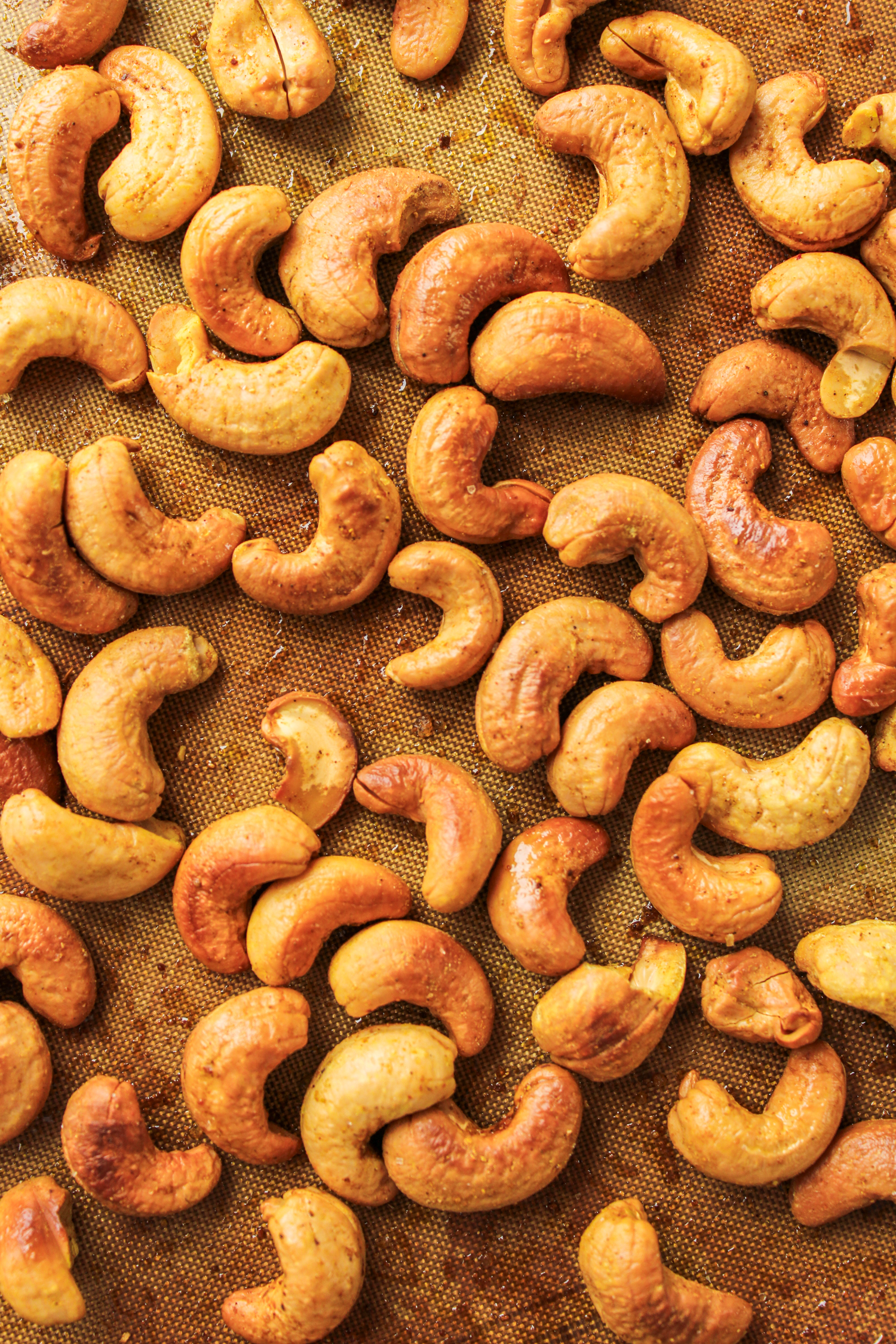 roasted curry cashews spread out on a baking tray