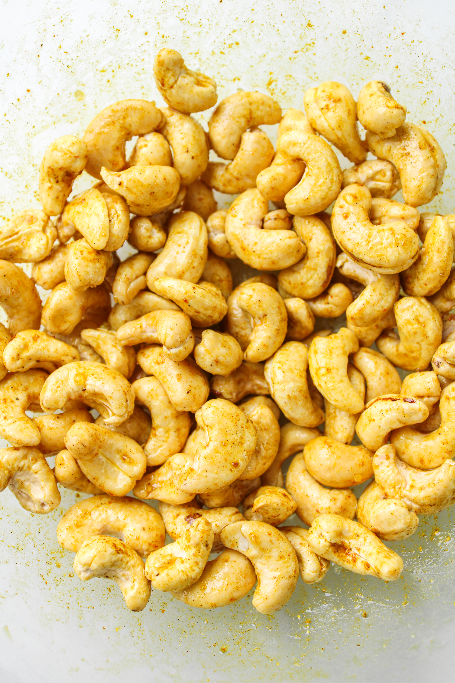 raw cashews with curry seasoning in a glass bowl