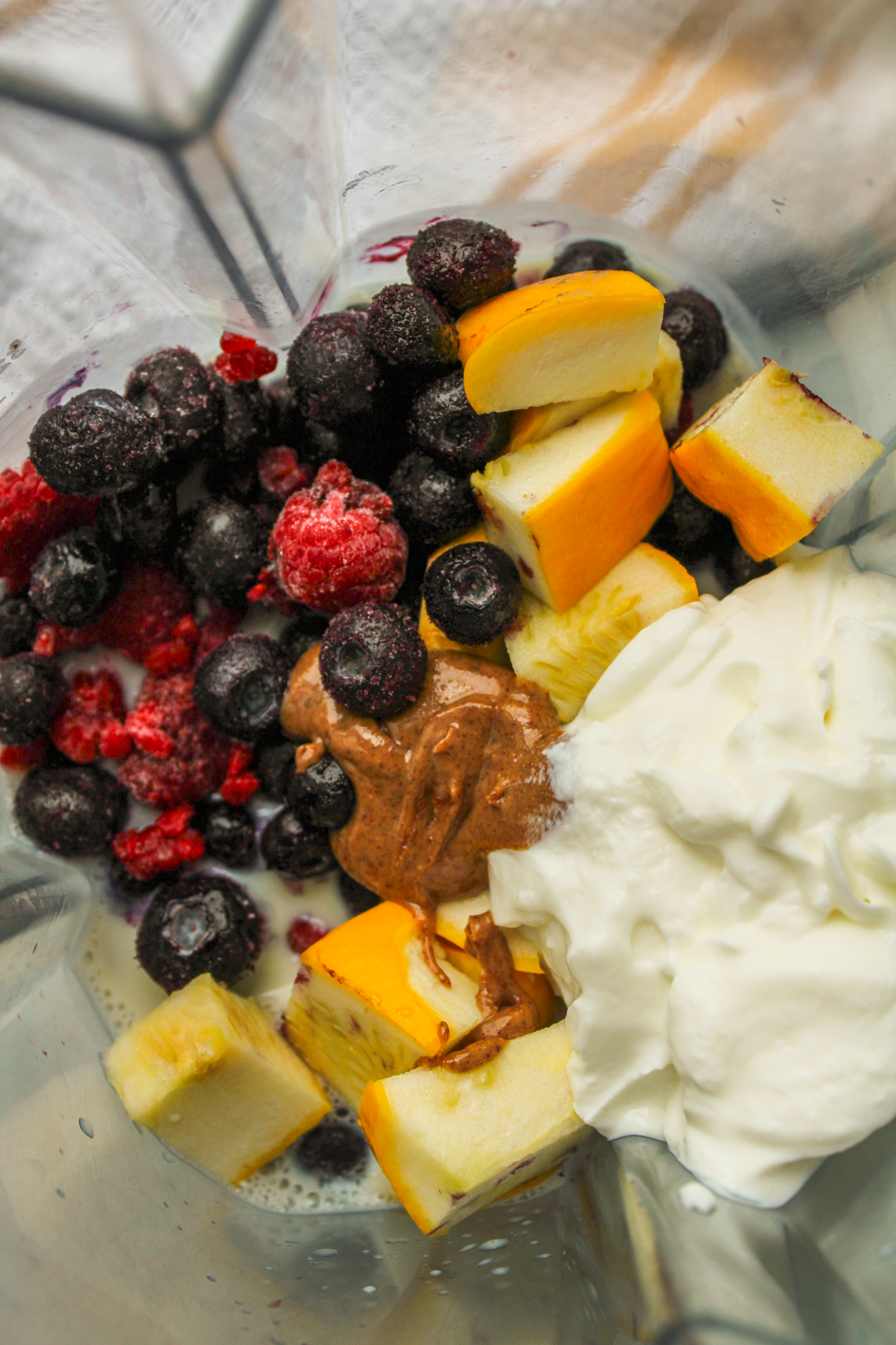 overhead shot of smoothie ingredients in a blender before being blended together