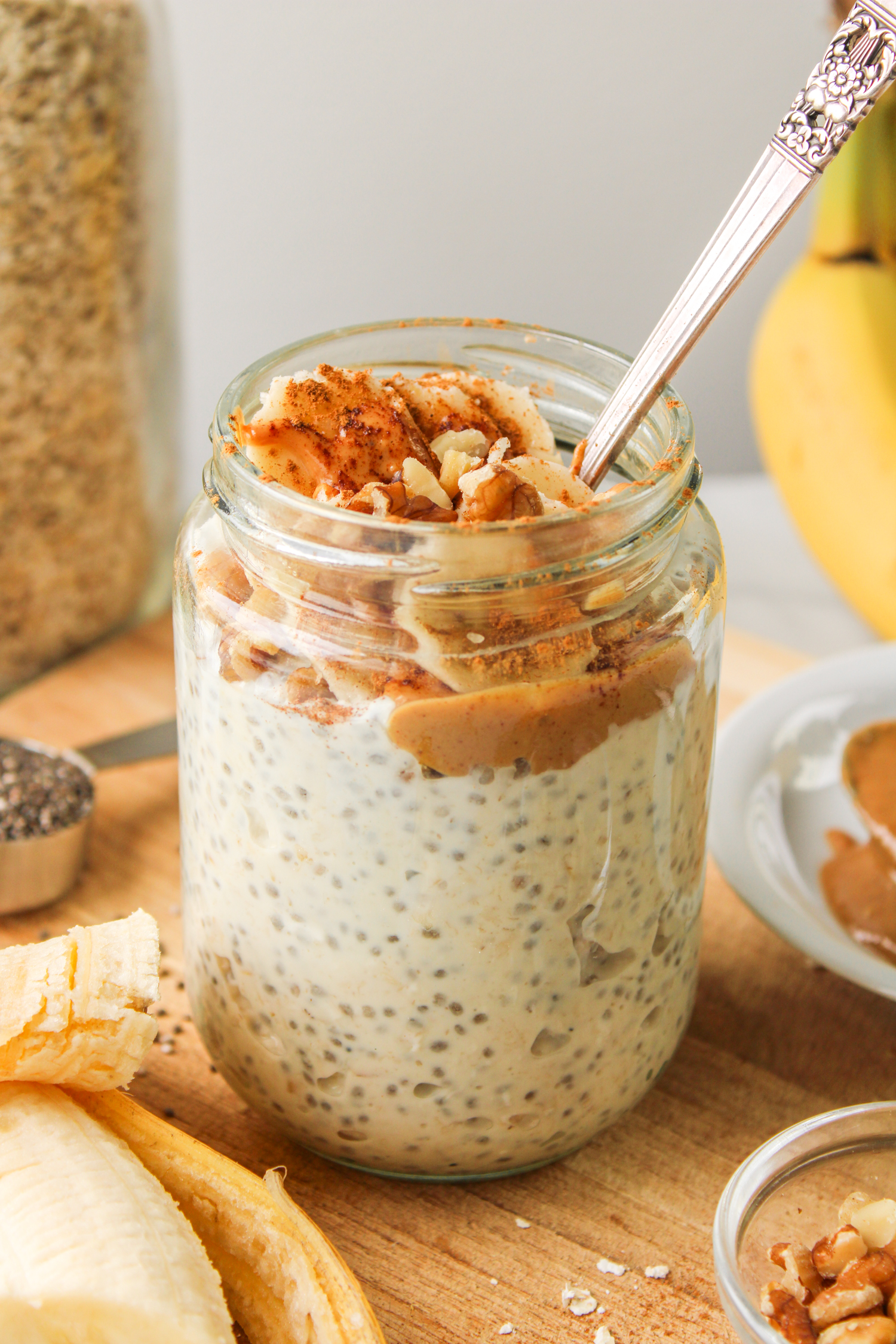 profile shot of banana chia overnight oats in a glass jar, topped with peanut butter, banana and cinnamon