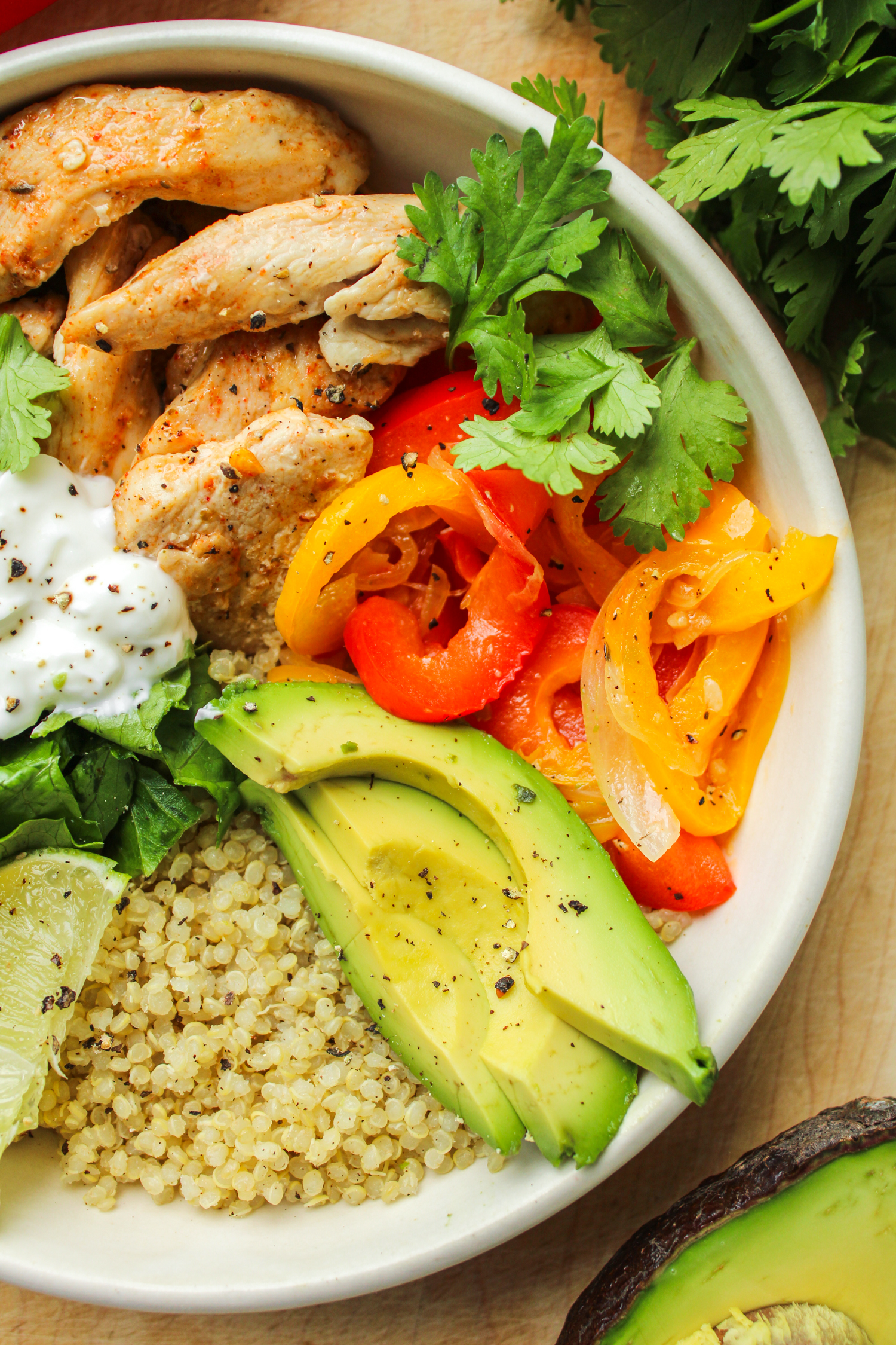 fajita quinoa bowl in a white ceramic dish on a wooden cutting board