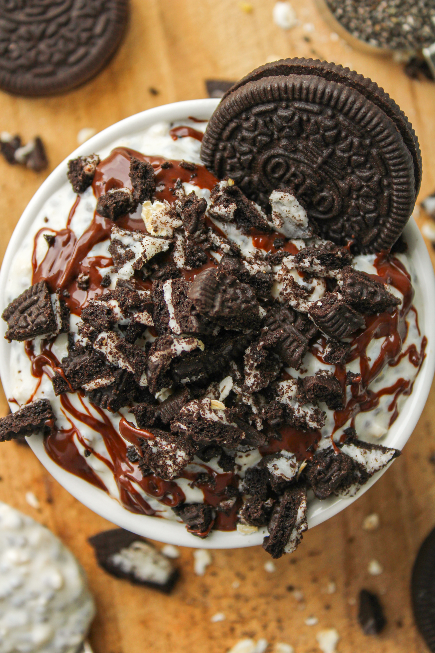 overhead shot of oreo oats in a white ceramic dish topped with melted chocolate and oreo crumbs