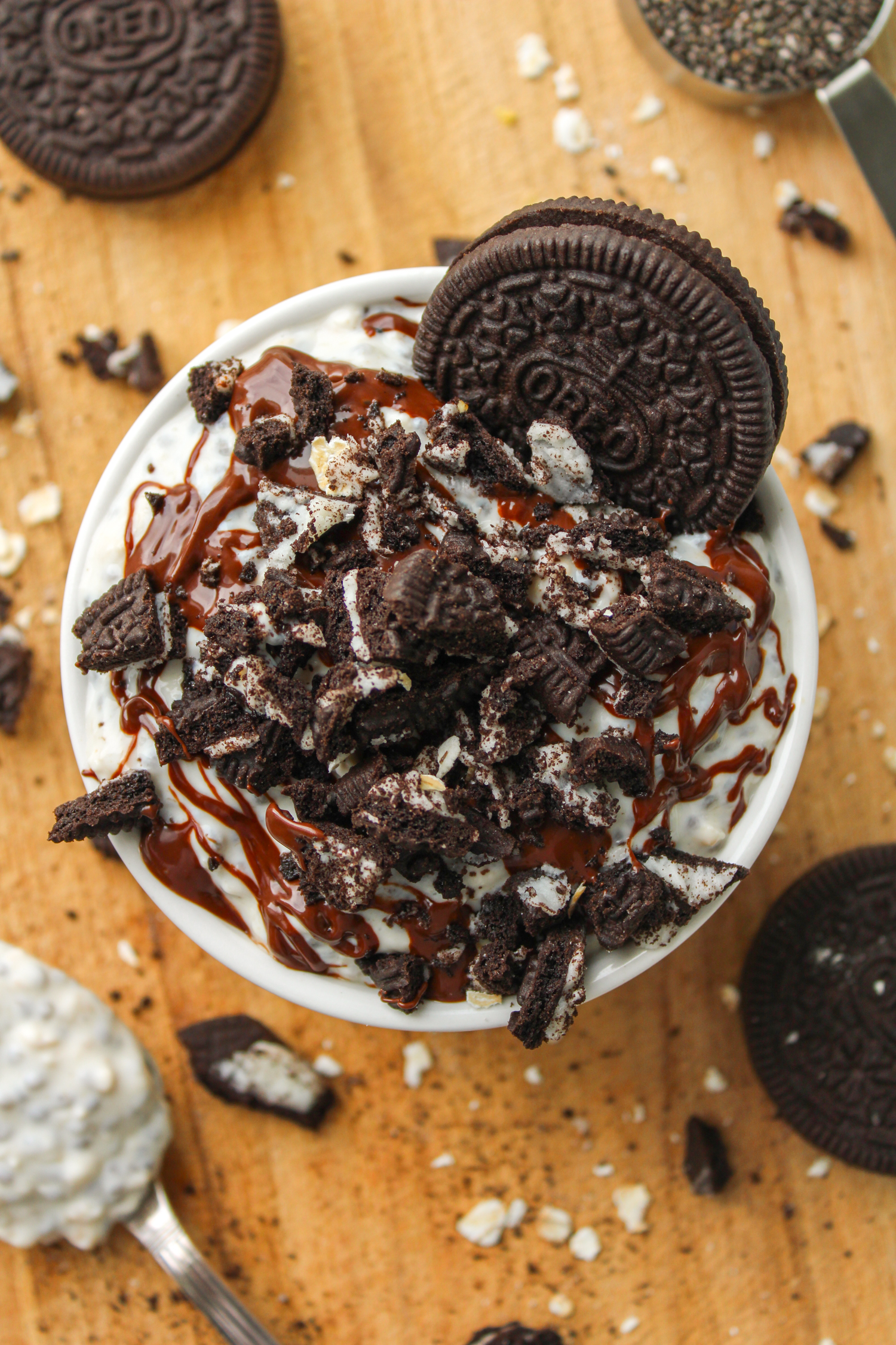 overhead shot of oreo overnight oats in a white ceramic dish topped with melted chocolate and oreo crumbs