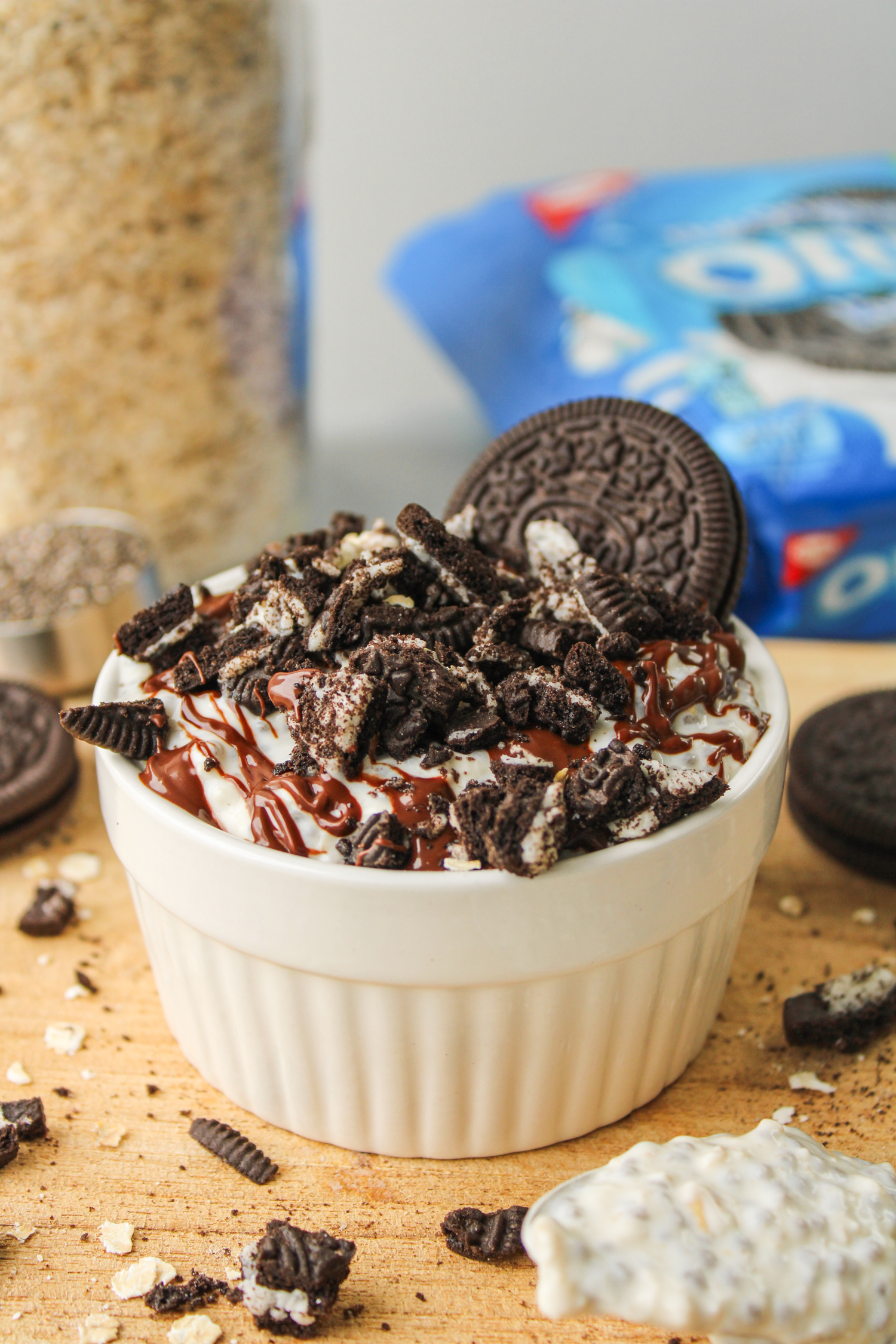 oreo overnight oats in a white ceramic dish topped with melted chocolate and oreo crumbs