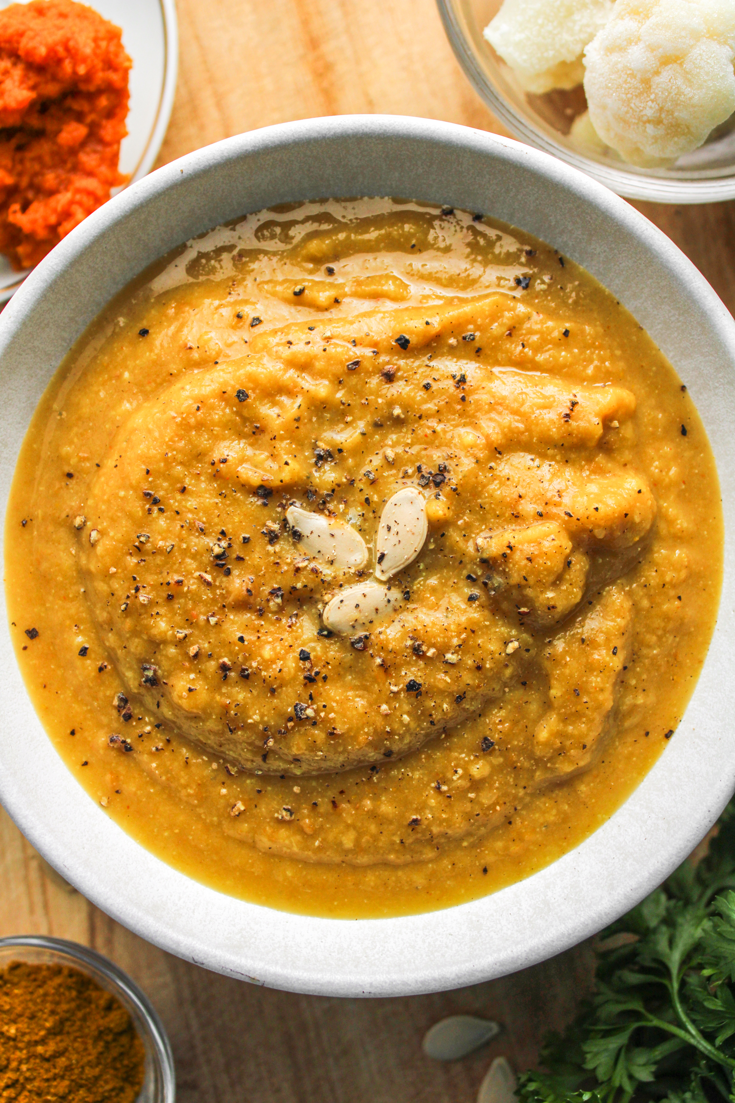 cauliflower pumpkin soup in white ceramic bowl topped with pumpkin seeds