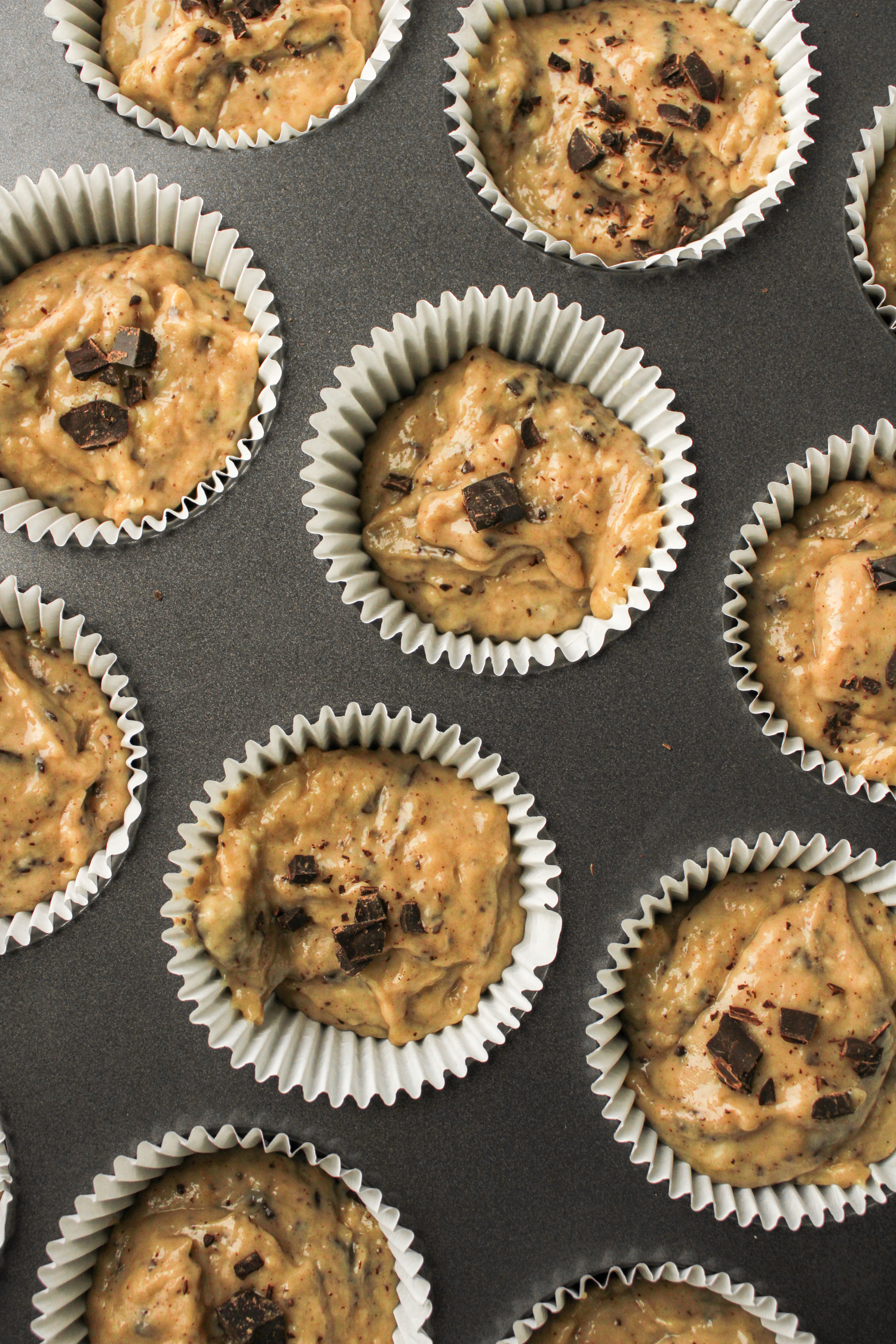 overhead shot of raw muffin batter in the muffin baking sheet