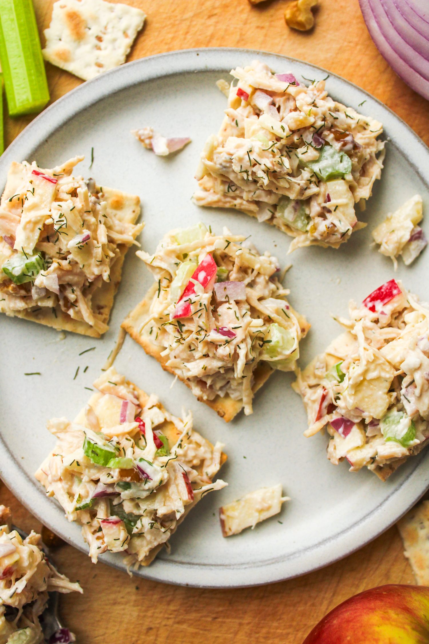 apple walnut chicken salad on top of crackers placed on a grey ceramic plate