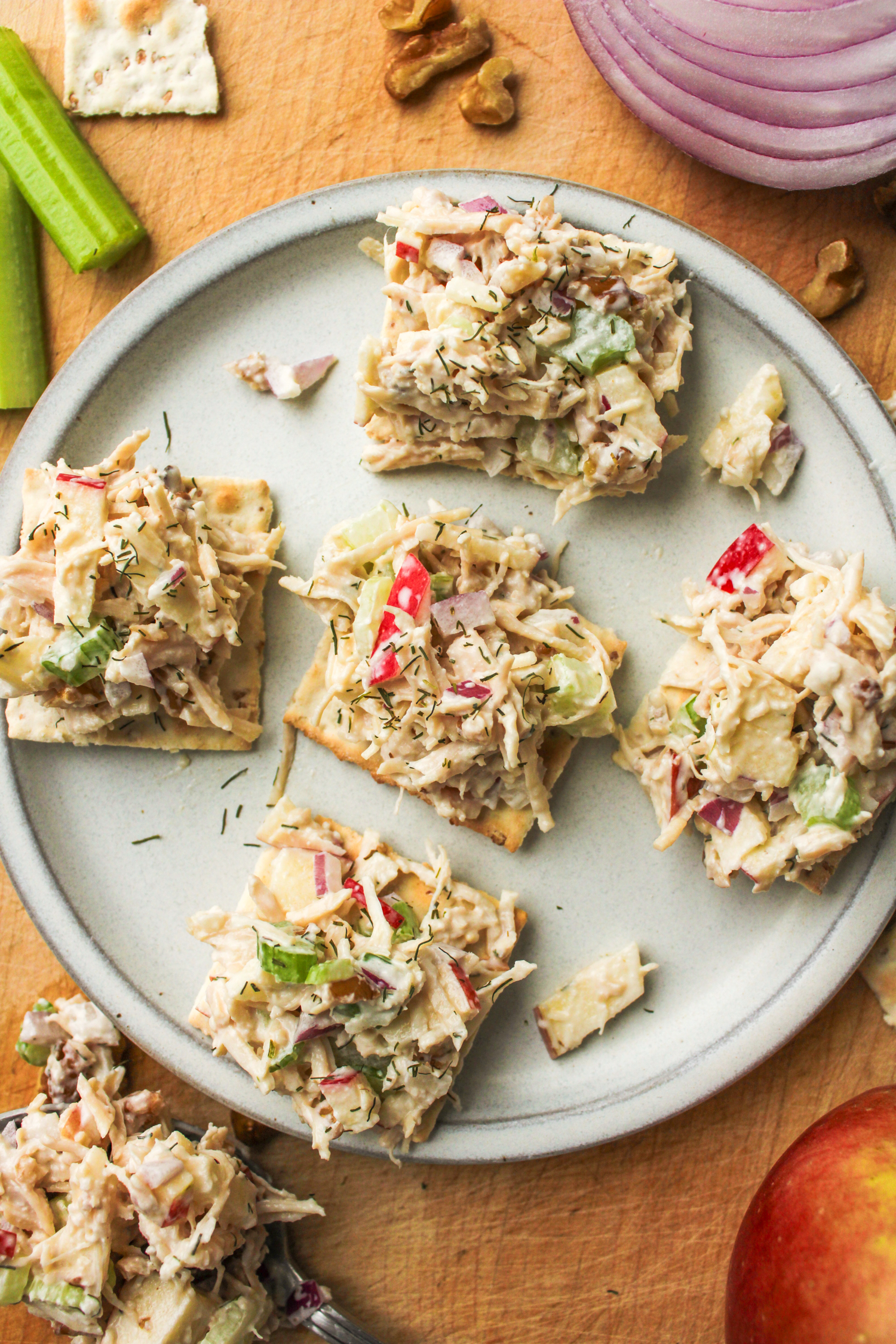 overhead shot of apple walnut chicken salad on top of crackers placed on a grey ceramic plate