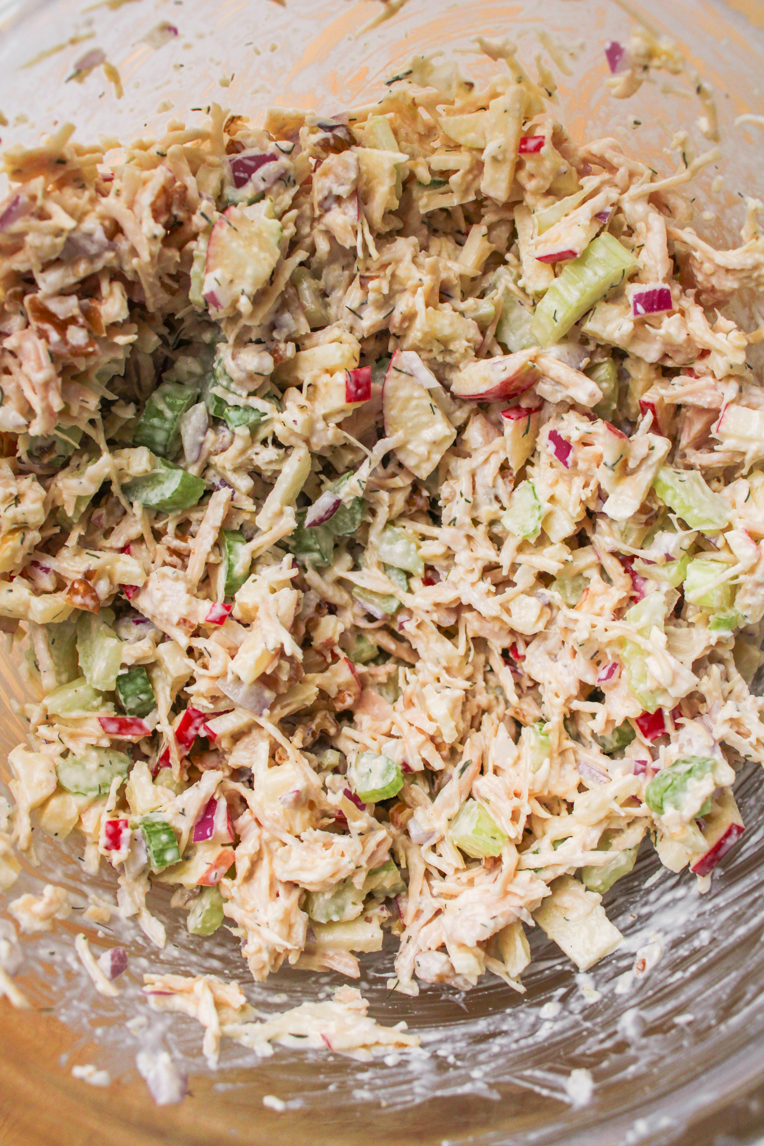 chicken salad ingredients mixed together in a glass bowl