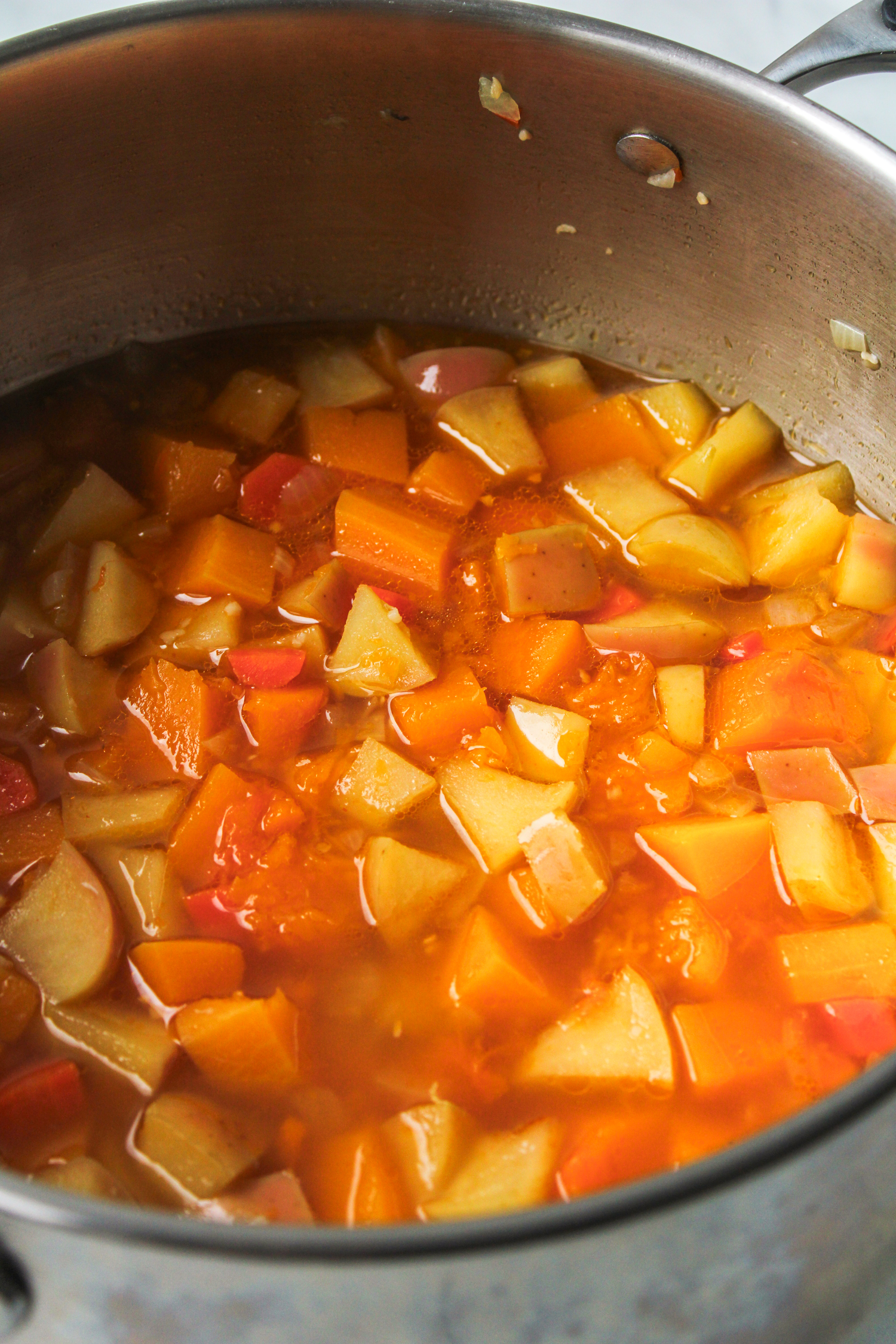 chopped vegetables and soup ingredients in a large stainless steel pot