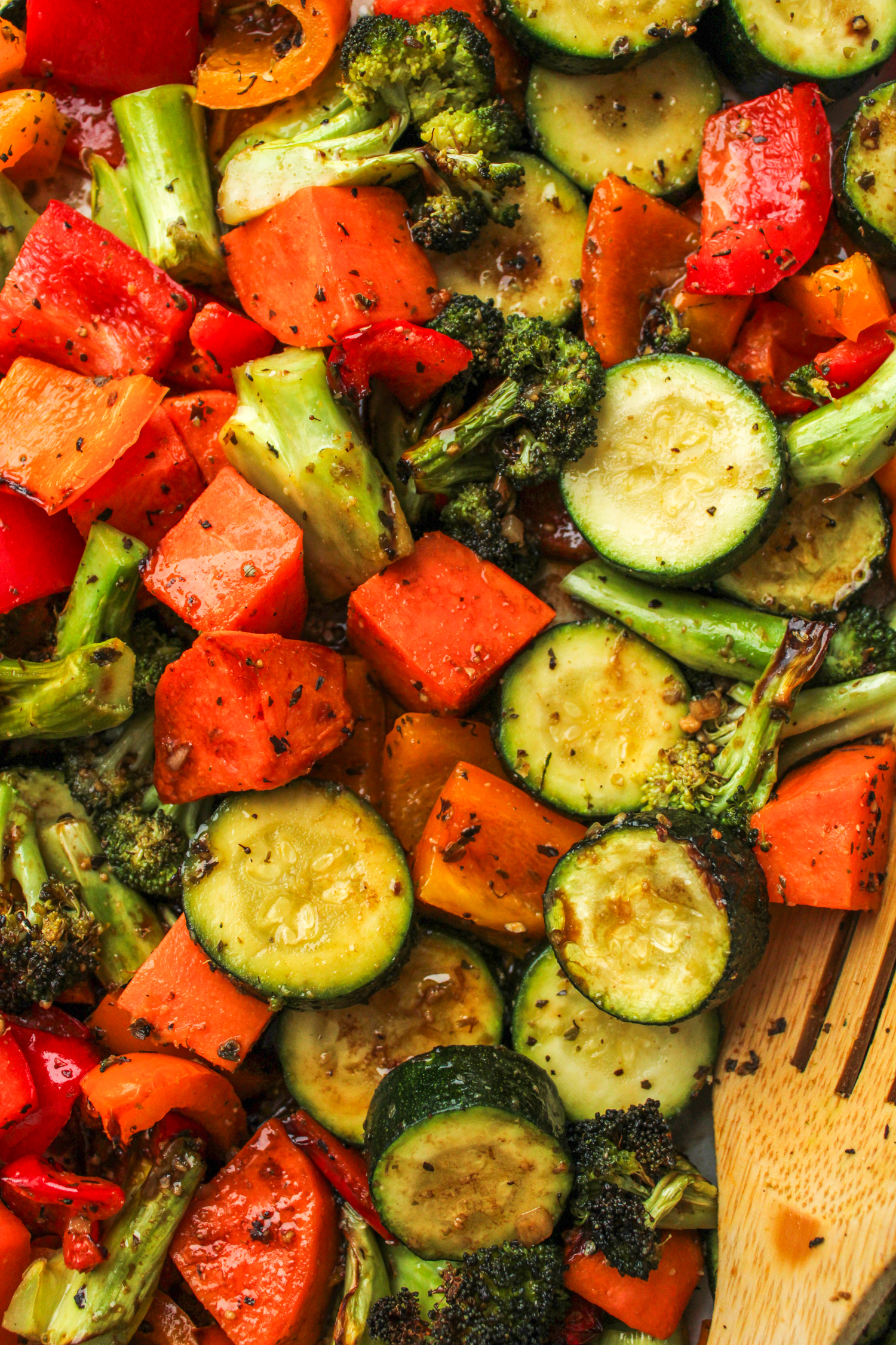 air fryer roasted vegetables with maple balsamic dressing and a wooden spoon to scoop them up