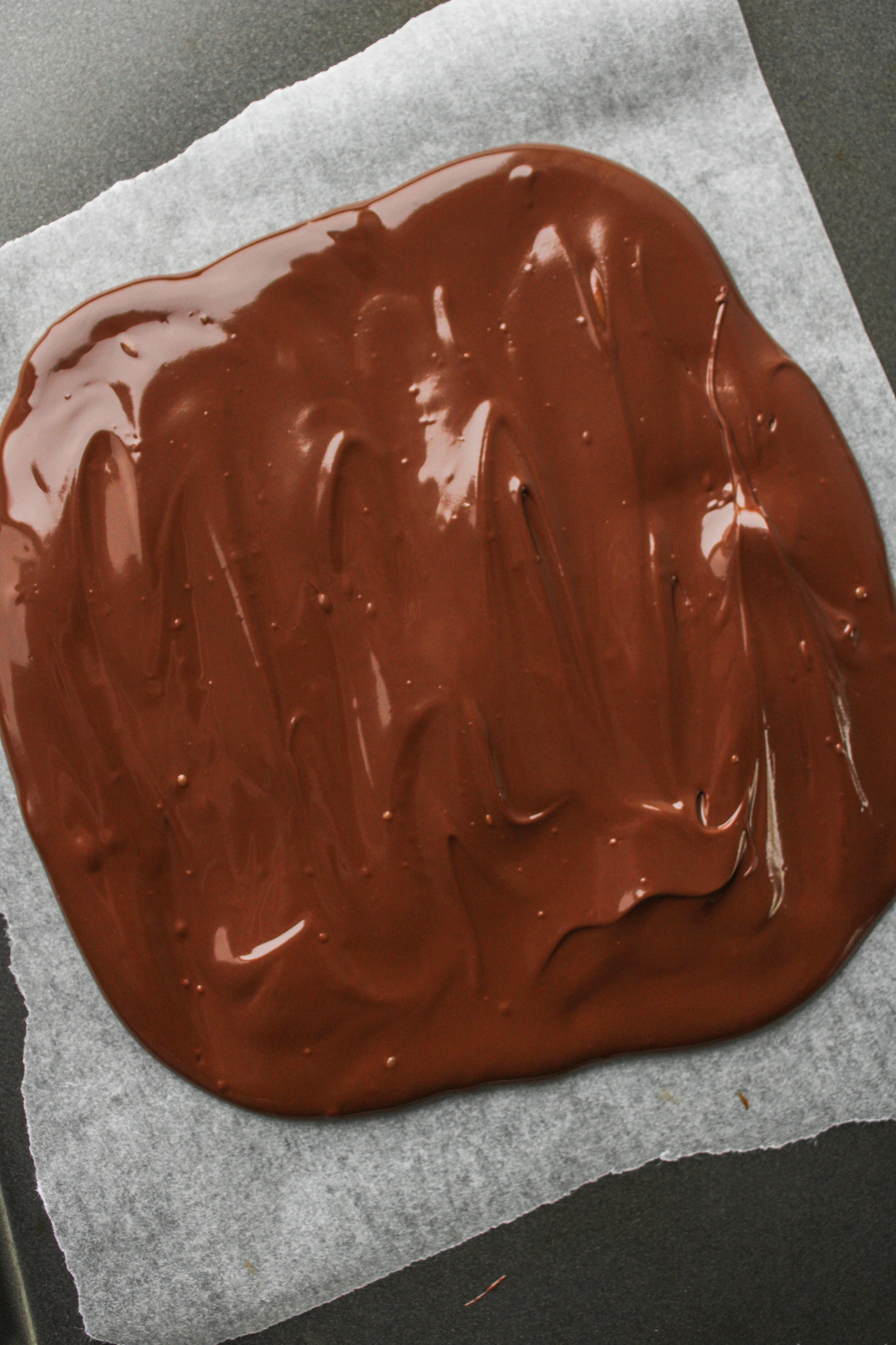 melted chocolate spread out on parchment paper 