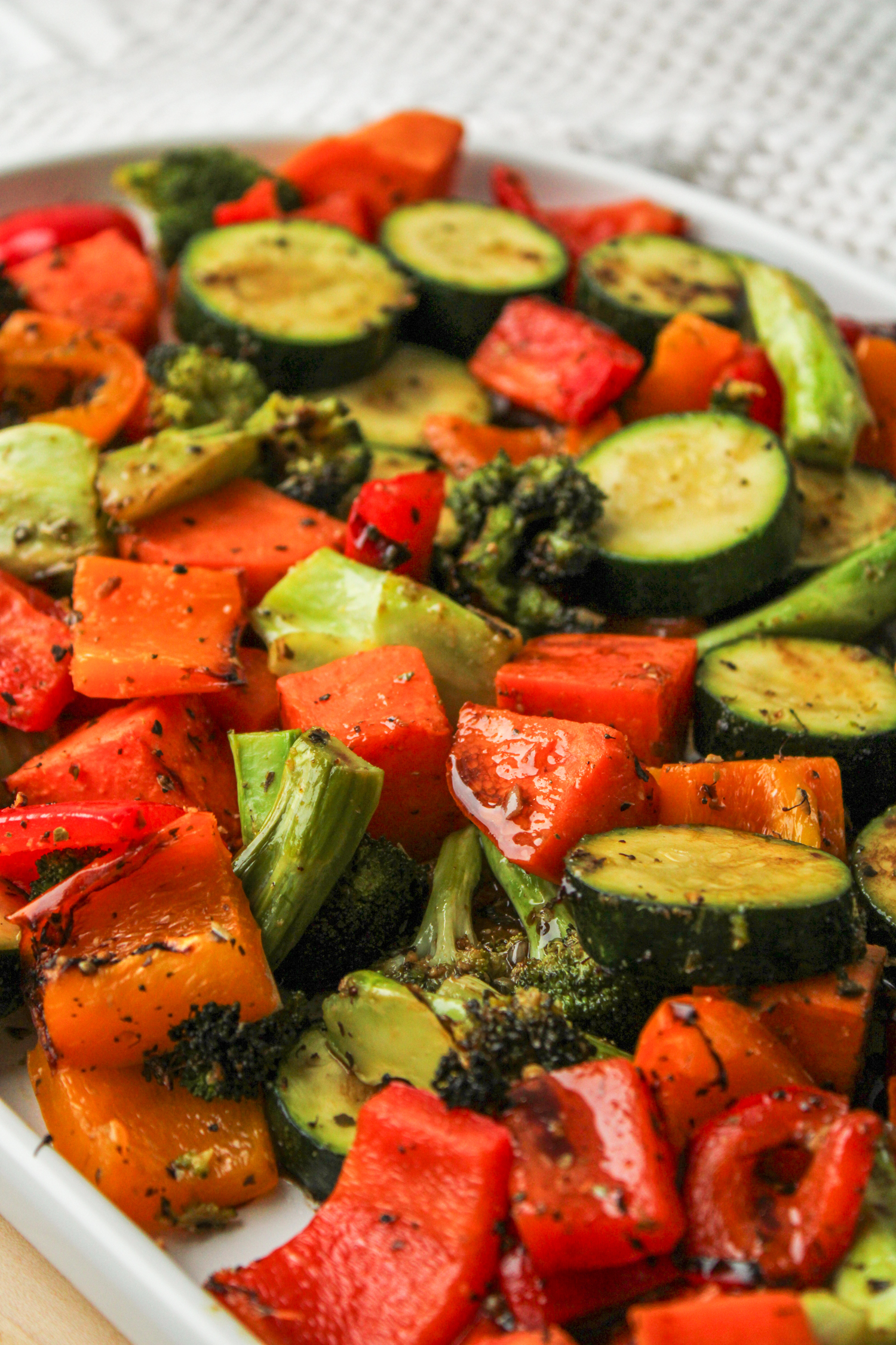 side profile shot of air fryer roasted vegetables with maple balsamic dressing on a large white ceramic serving dish