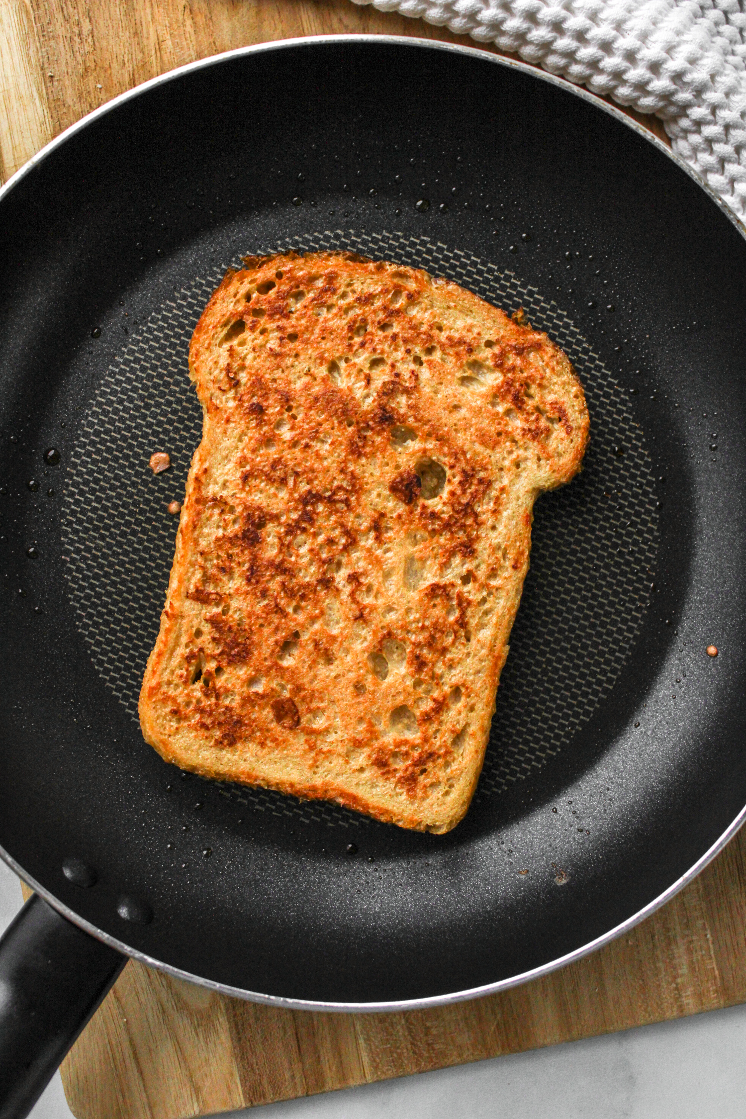 sourdough french toast cooking on a black frying pan