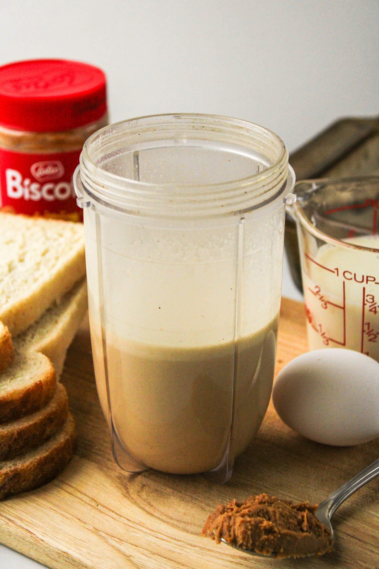 egg and milk mixture in a blender cup with the french toast ingredients behind it