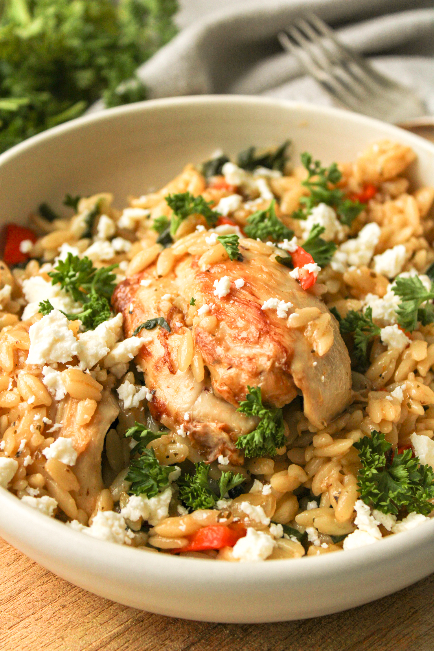 Mediterranean chicken orzo bake in a beige ceramic dish