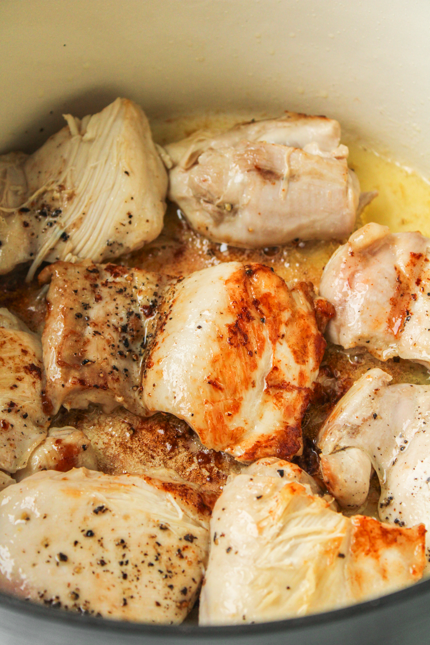 chicken thighs cooking in a large ceramic pot