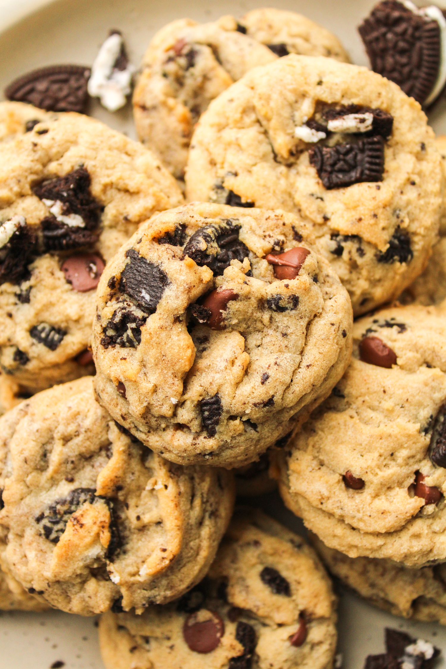 zoomed in oreo and chocolate chips cookies piled on top of each other on a ceramic plate