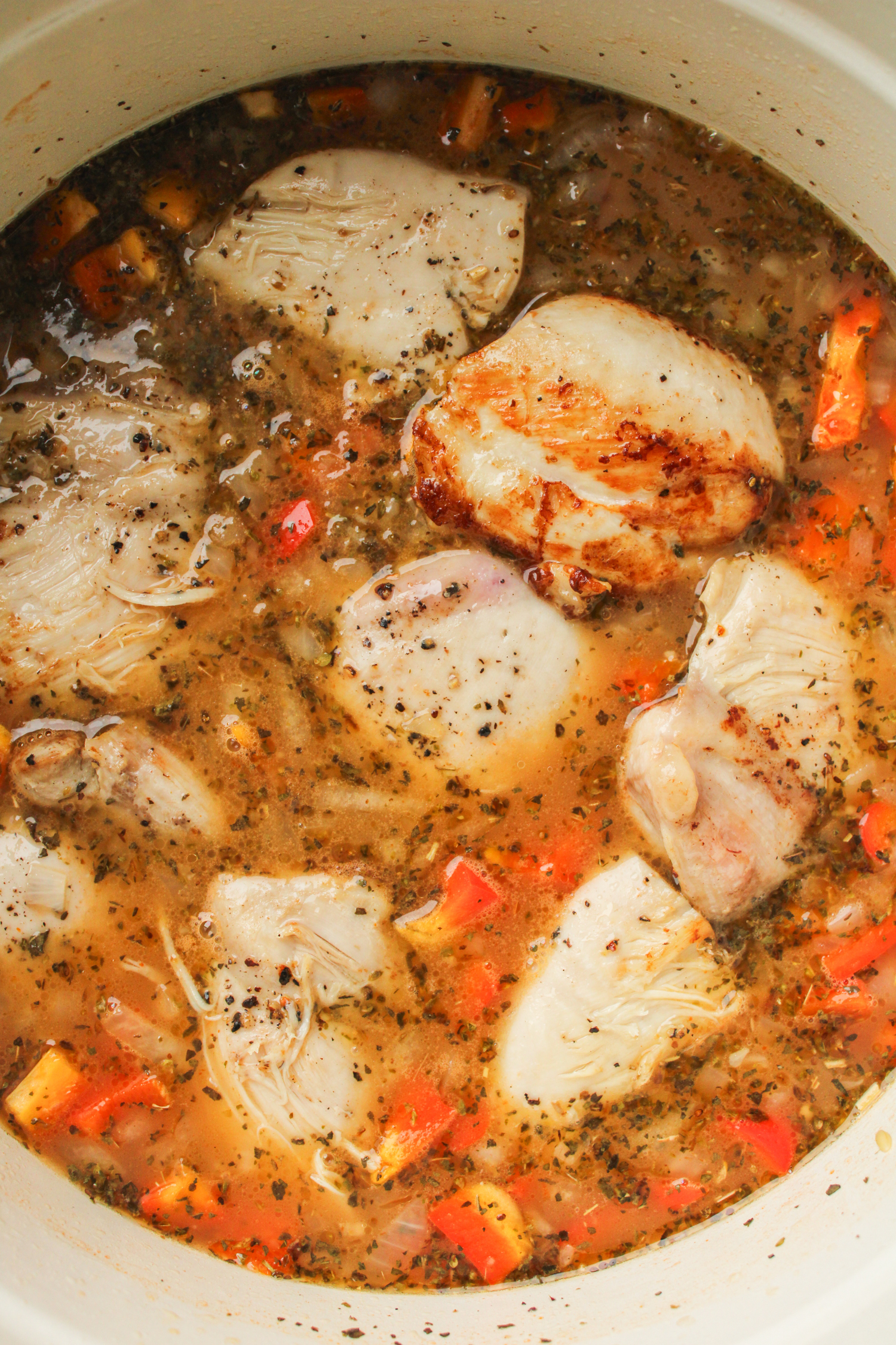 chicken thighs in chicken broth and orzo in a large cooking pot