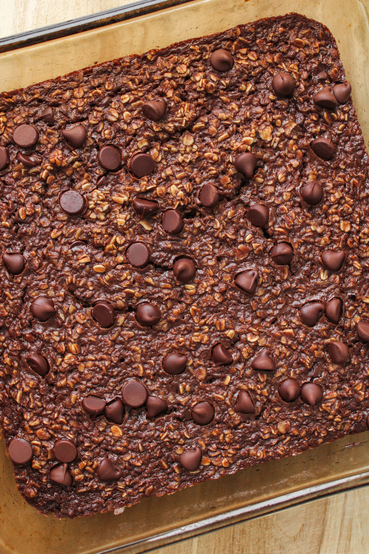 baked chocolate oats in an 8x8" pyrex baking dish on top of a wooden cutting board