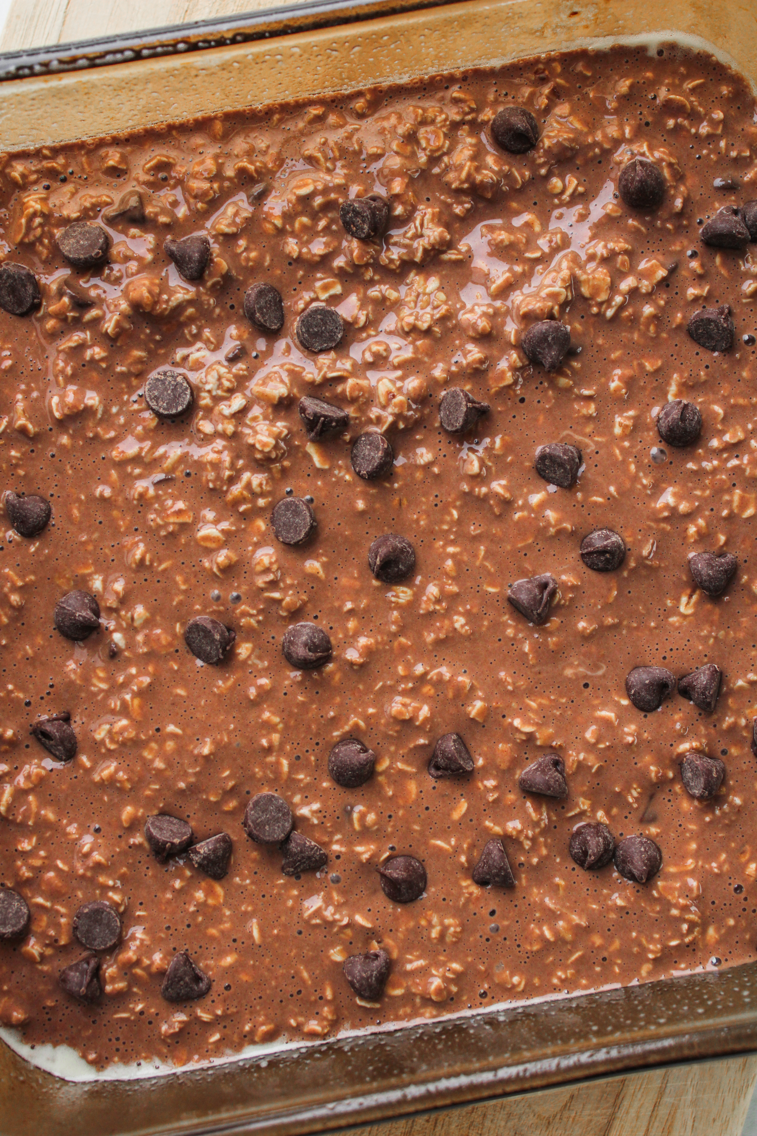 unbaked chocolate oatmeal batter in an 8x8" pyrex dish topped with chocolate chips