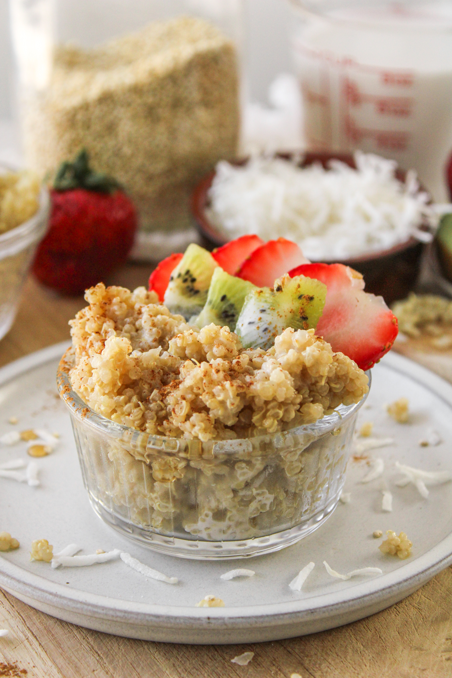 quinoa coconut milk porridge in a small glass bowl topped with kiwi and strawberries
