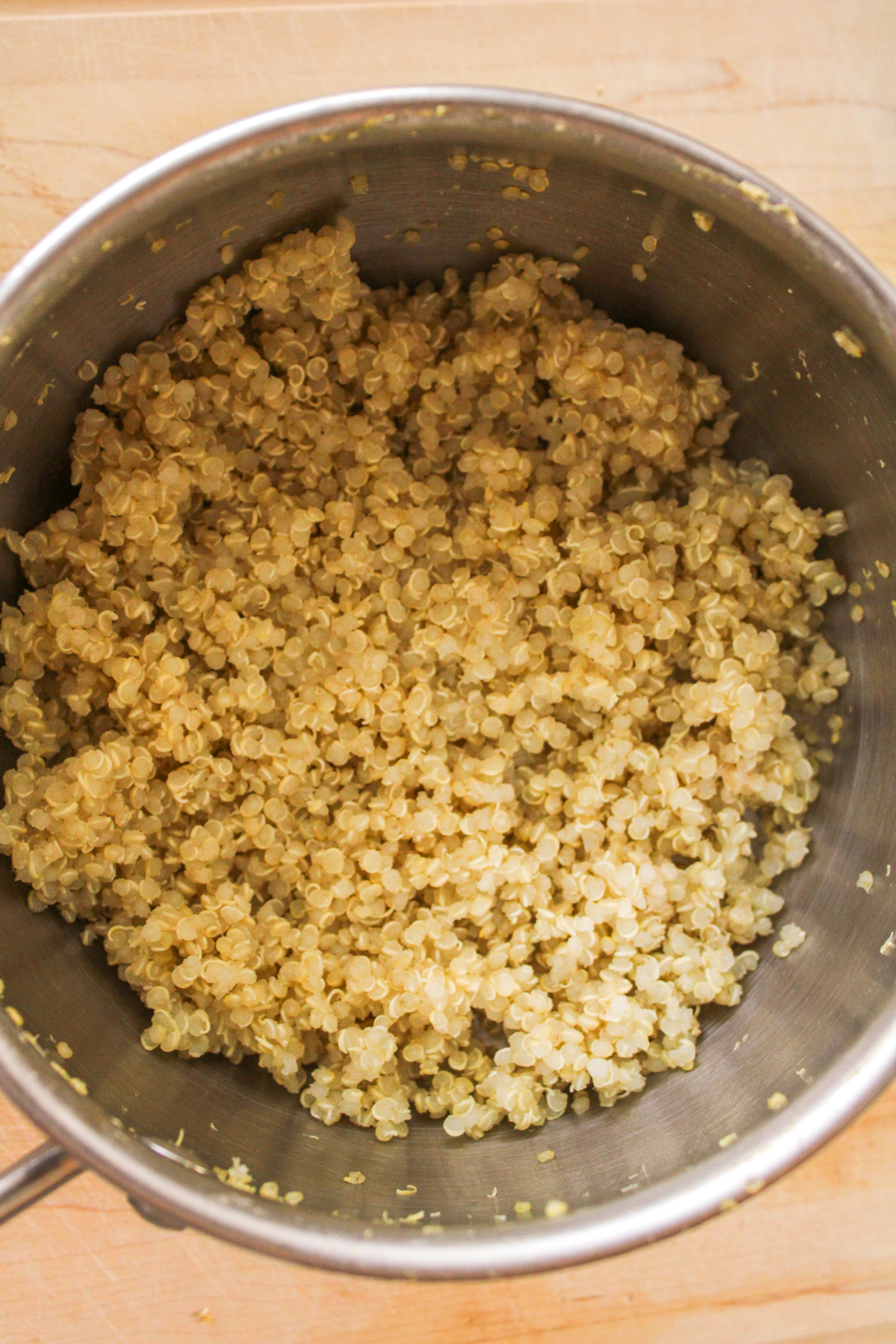 cooked quinoa in a small pot on a wooden cutting board