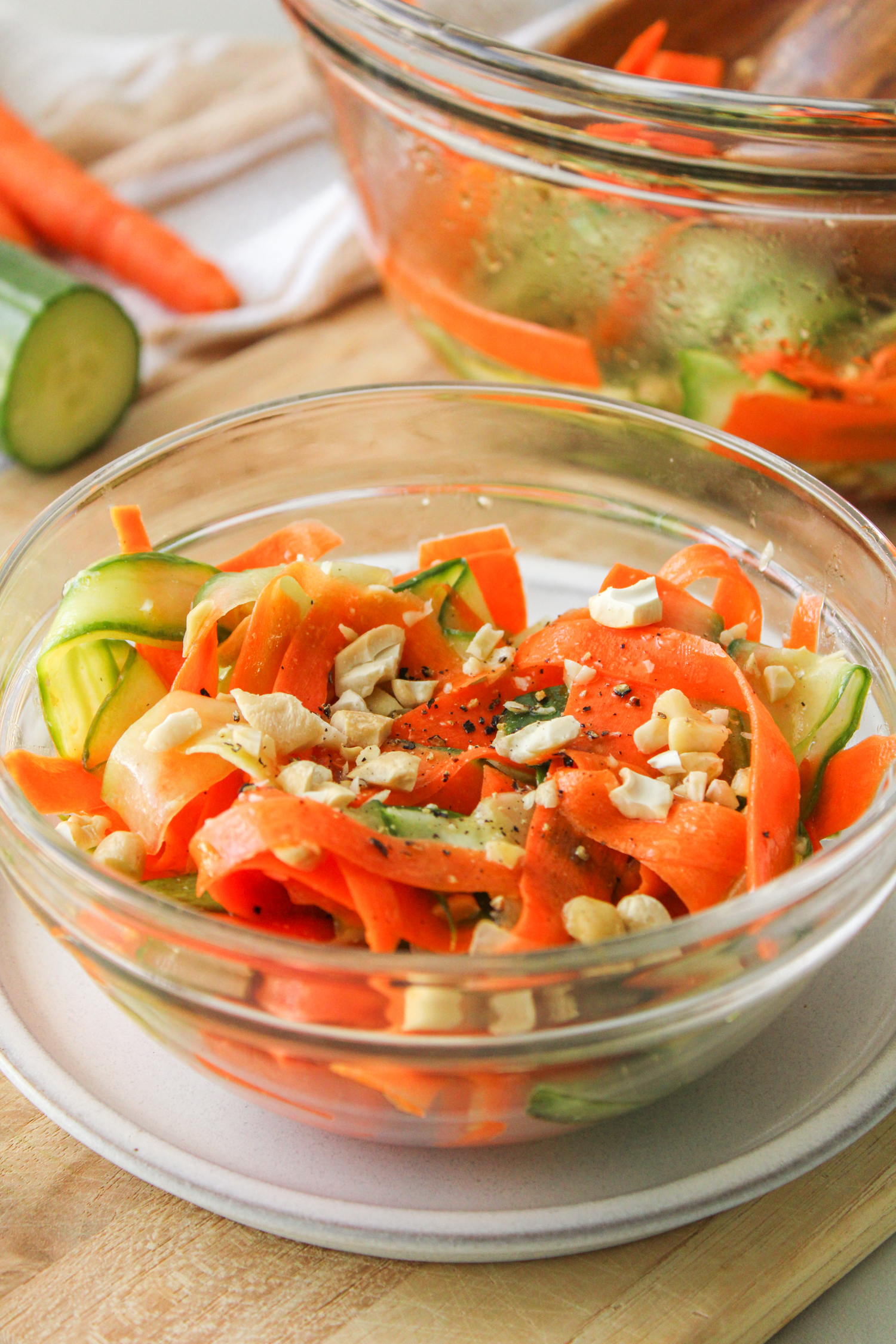 carrot cucumber salad in a glass bowl on a wooden cutting board