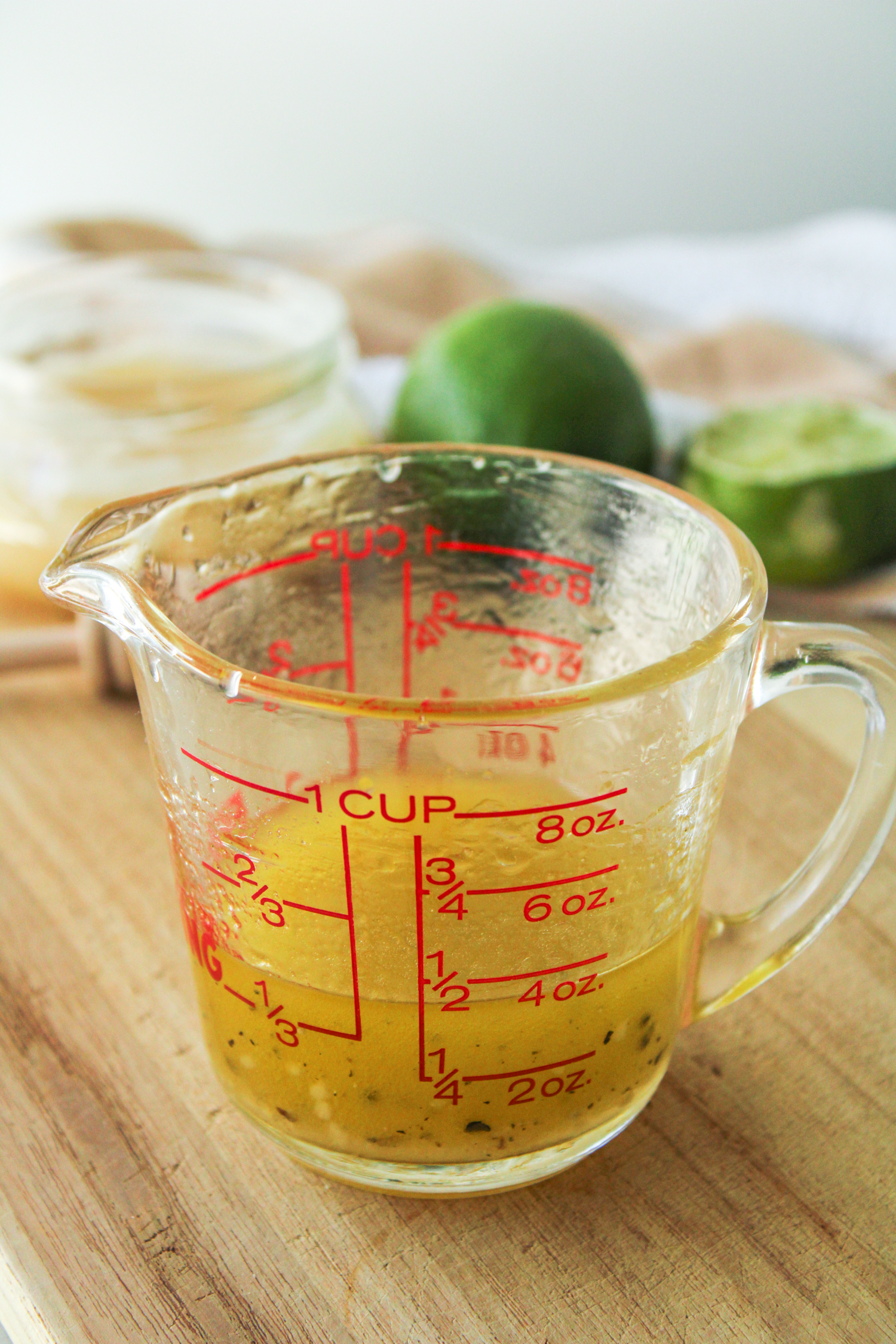 honey lime vinaigrette in a glass measuring cup on a wooden board